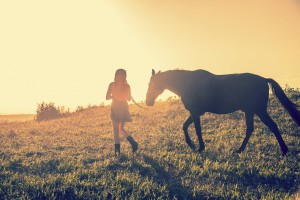 A woman leading a horse in a sunset